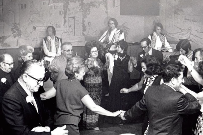 Group of people dancing to Greek music at Greek restaurant Tops 24 Restaurant owned by George Sepranos in celebration of Peter Wells’ 80th birthday.